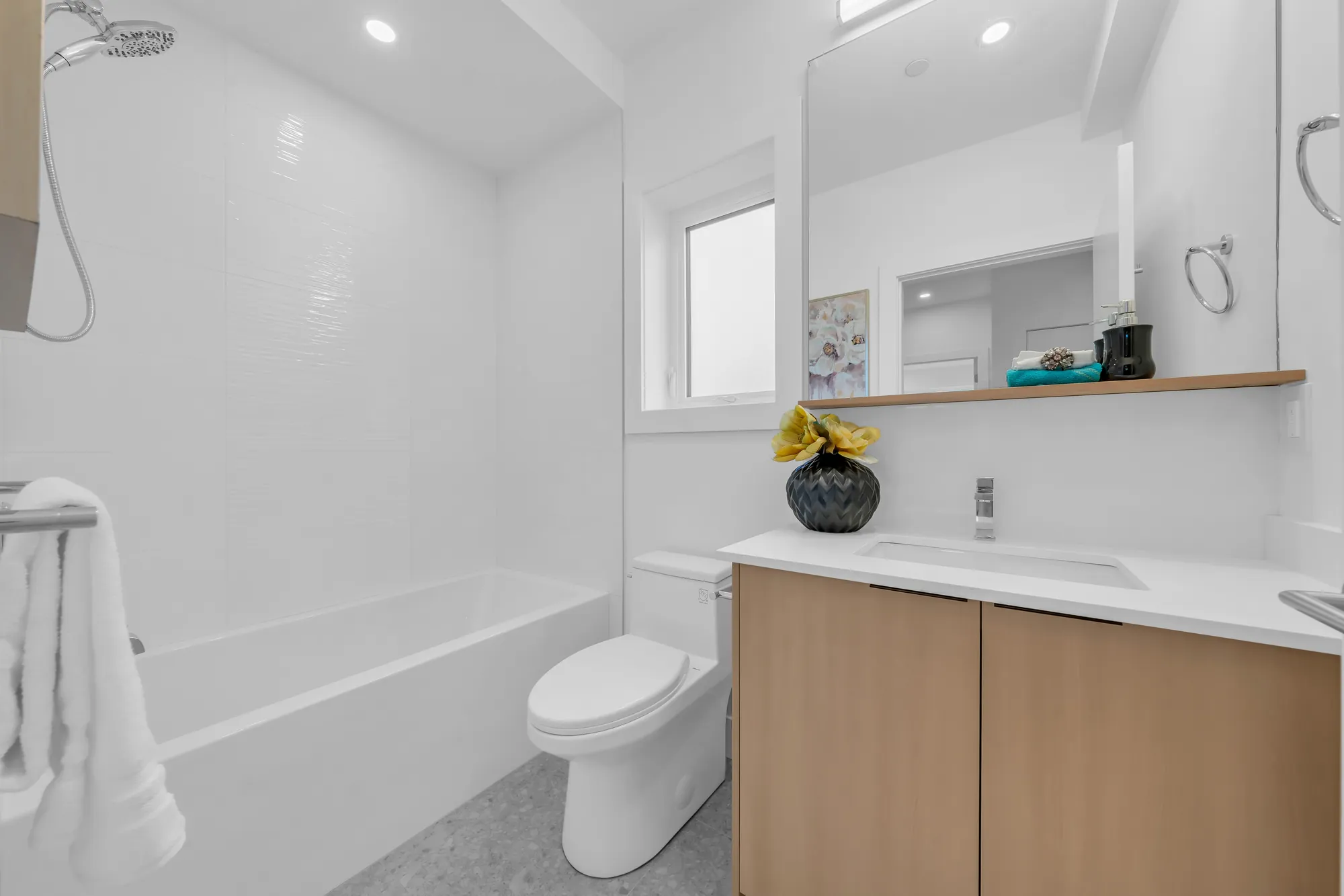 The second bathroom: a tub with a rain shower head, white tile, an oak vanity, a toilet