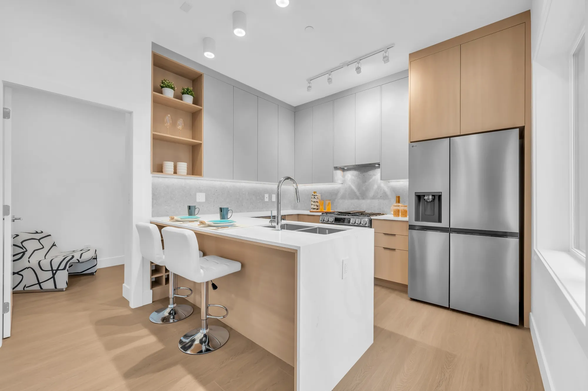 The kitchen from the dining side: the island and stools, a stainless double-door fridge set in oak cabinets