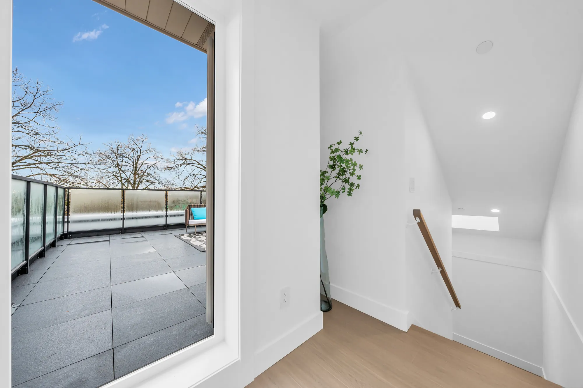 The loft toward the roof terrace: a large window onto the terrace and its glass railing, the stair rail