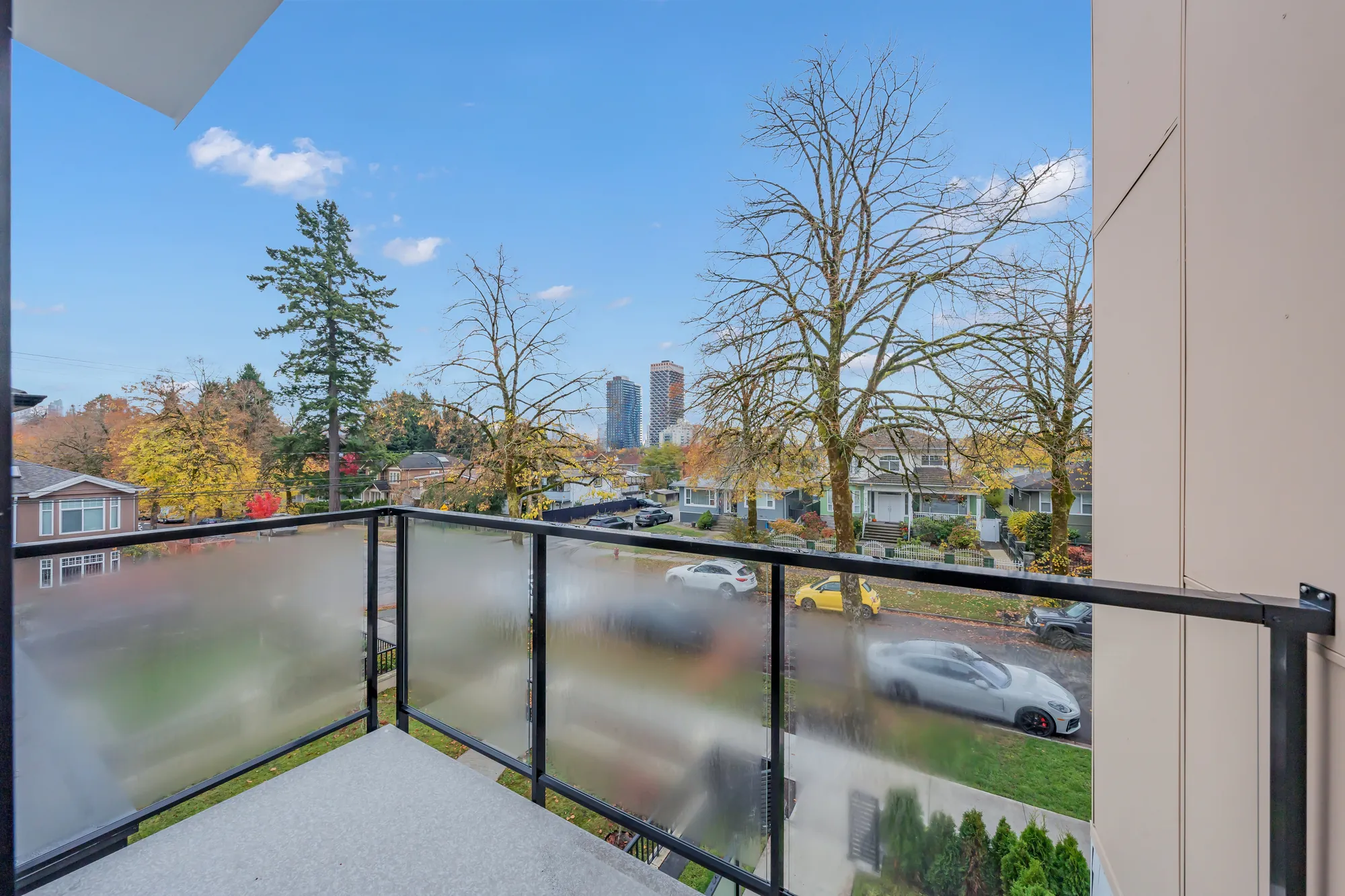 The bedroom balcony: a glass railing over the street, the trees and the houses across