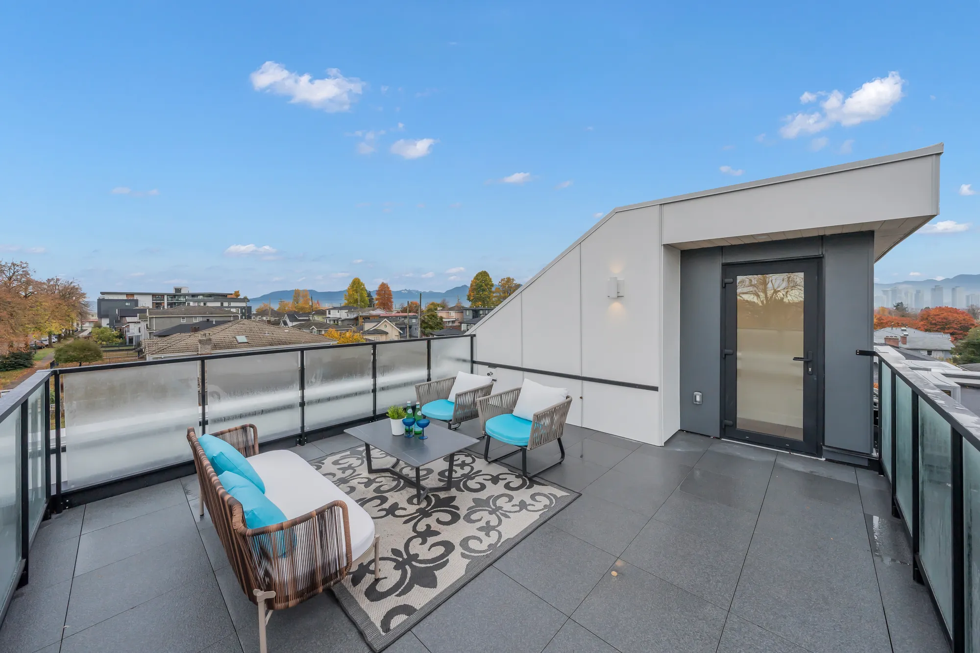 The roof terrace toward the loft: the doorway in white panels, the seating, hills in the distance