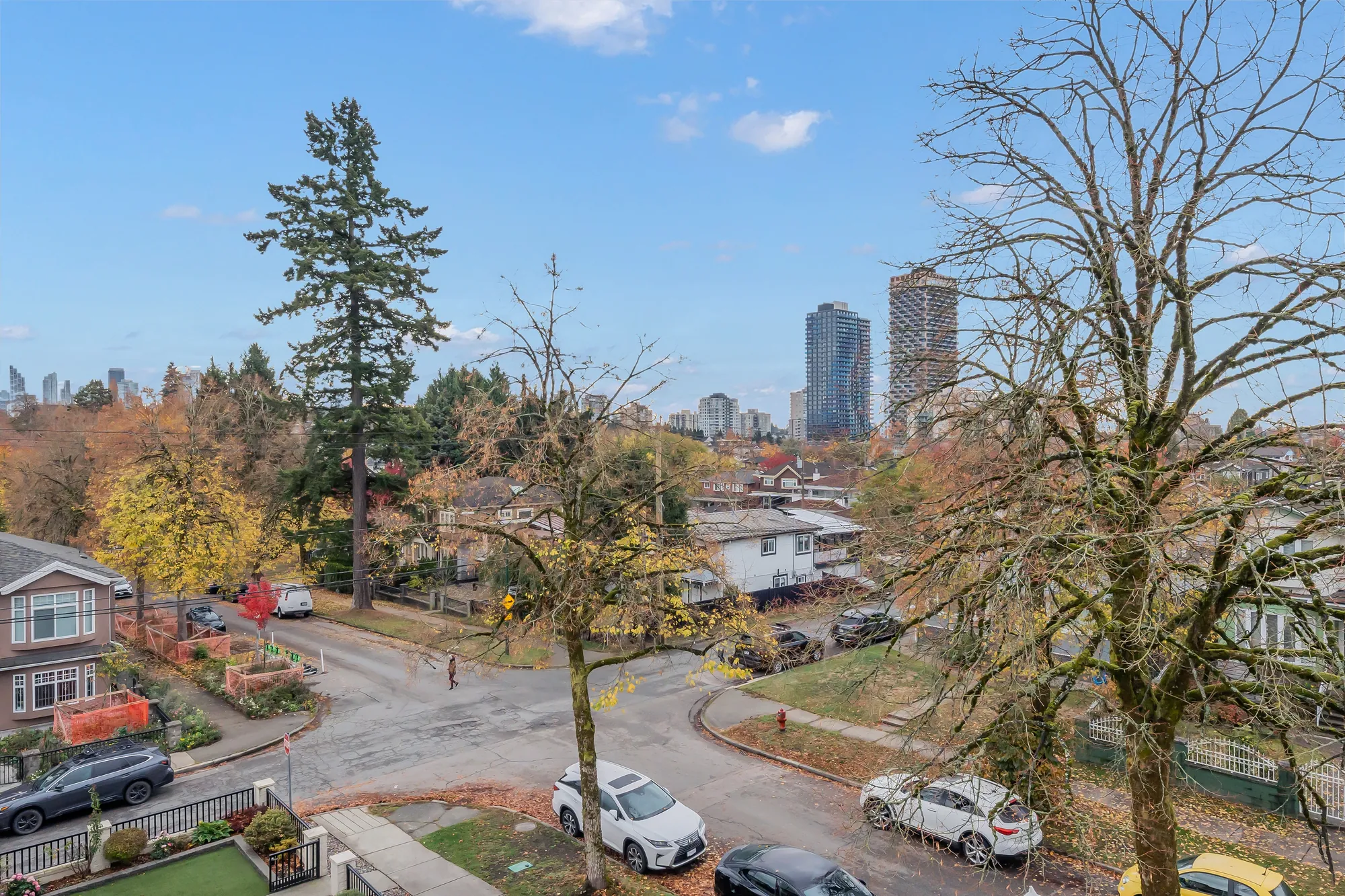 From the roof: a street corner, trees and two towers on the skyline