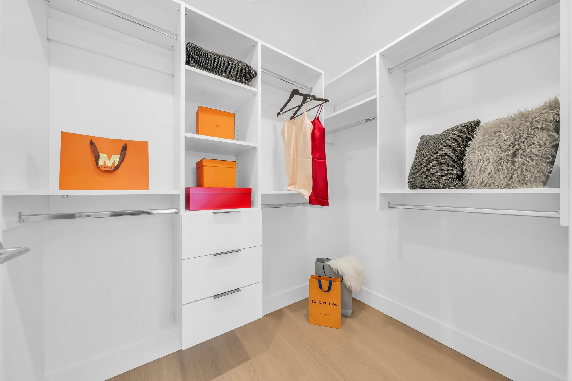 The walk-in closet: white open shelves, drawers and hanging rails